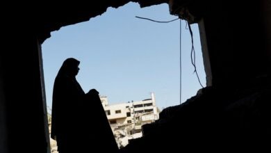 صورة أرشيفية تظهر امرأة فلسطينية تتفقد منزلها المتضرر عقب غارة إسرائيلية استهدفت مسجداً مجاوراً في مدينة غزة (29 يوليو/تموز 2026).