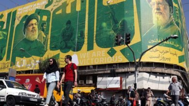 يمر إيرانيون أمام لوحة إعلانية تظهر المرشد الأعلى الإيراني السابق علي خامنئي (يمين) والزعيم السابق لحزب الله حسن نصر الله (يسار)، في طهران