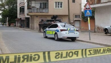 سيارة شرطة تركية وآلية عسكرية خلفها جندي على جانب الطريق مع وجود شريط أصفر في أسفل الصورة لقطع الطريق