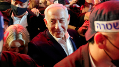 رئيس الوزراء الإسرائيلي بنيامين نتنياهو يبتسم وهو ينظر لشيء وسط مجموعة من الأشخاص