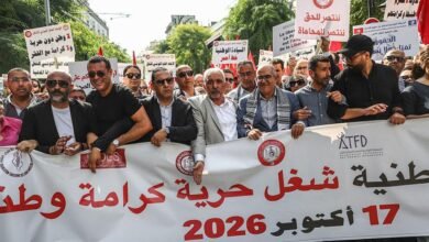 تونس: ما دلالات اتساع دائرة الرافضين لسياسات الرئيس قيس سعيّد؟ 3 متظاهرون تونسيون يحملون لافتات عدة، من بينها لافتة بيضاء كبيرة كُتب عليها: شعار "شغل، حرية، كرامة وطنية".
